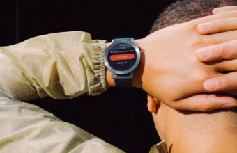 Smartwatch au poignet d'une personne affichant fréquence cardiaque et entraînement.