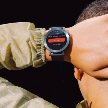Smartwatch au poignet d'une personne affichant fréquence cardiaque et entraînement.