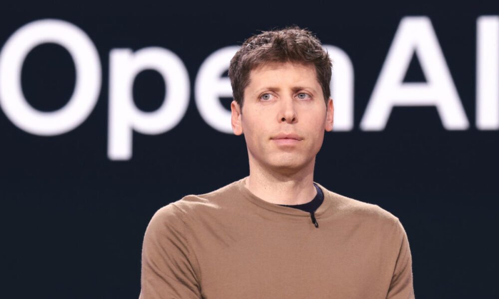 Sam Altman, PDG d'OpenAI, devant le logo de la société.