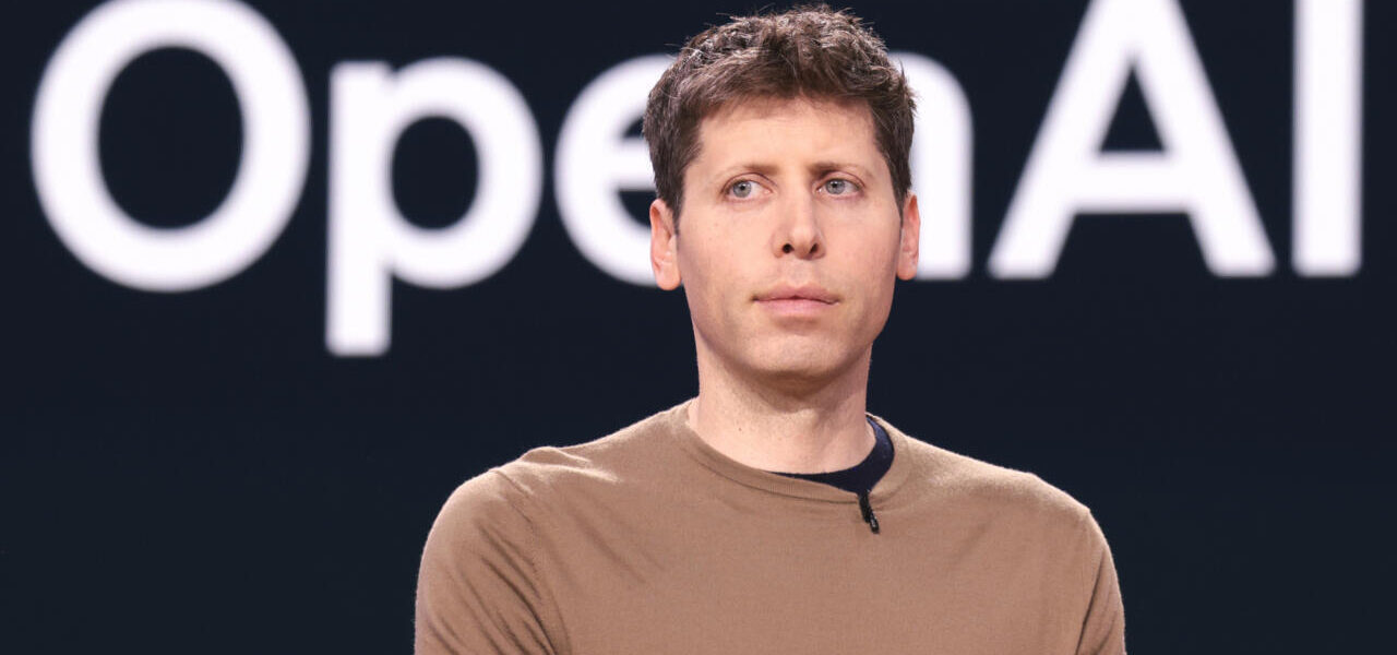 Sam Altman, PDG d'OpenAI, devant le logo de la société.