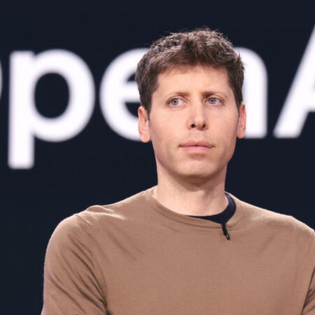 Sam Altman, PDG d'OpenAI, devant le logo de la société.