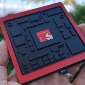 Main tenant une puce Snapdragon 8 Elite rouge et noire.