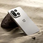 Design du OnePlus 16 : OnePlus miserait sur la continuité Smartphone OnePlus gris clair sur sable avec rochers.