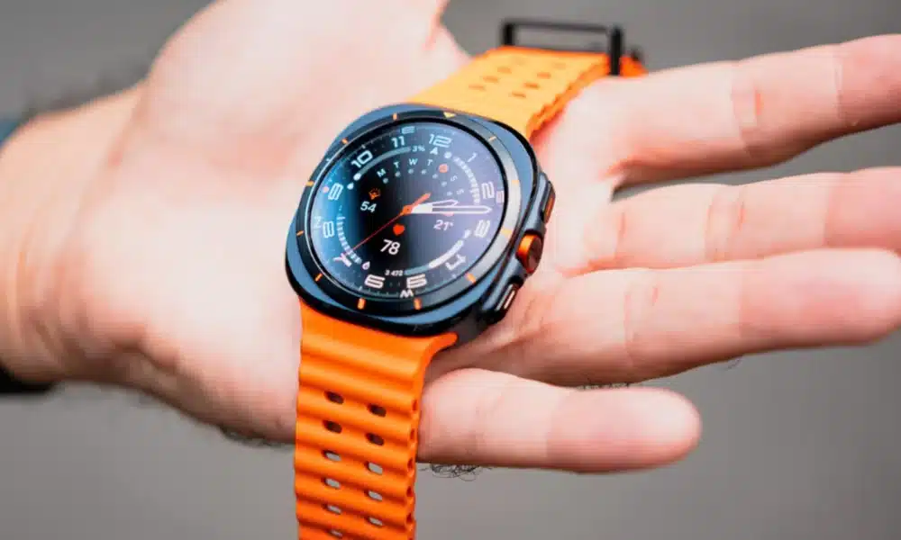 Montre connectée noire et orange affichant des données sur une main.