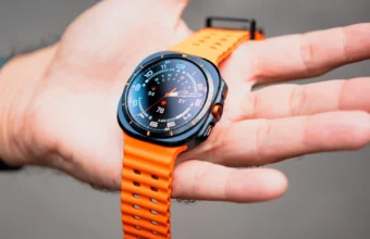 Montre connectée noire et orange affichant des données sur une main.