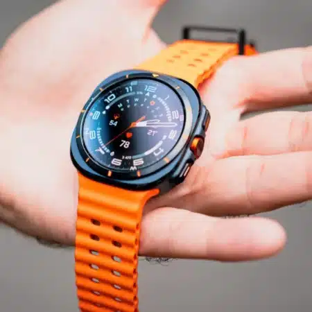 Montre connectée noire et orange affichant des données sur une main.