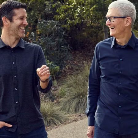 Deux hommes souriants, dont Tim Cook, marchant ensemble en extérieur.