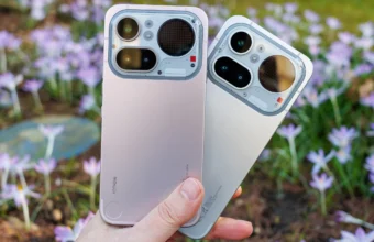 Deux Nothing Phone (2a) rose et blanc tenus près de fleurs.