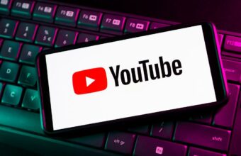 Logo YouTube sur smartphone posé sur clavier d'ordinateur rétroéclairé.