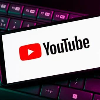 Logo YouTube sur smartphone posé sur clavier d'ordinateur rétroéclairé.