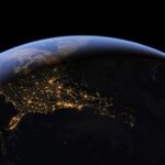 Google Earth suspend son générateur d’images IA après seulement un jour La Terre depuis l'espace, villes illuminées, ligne jour-nuit.