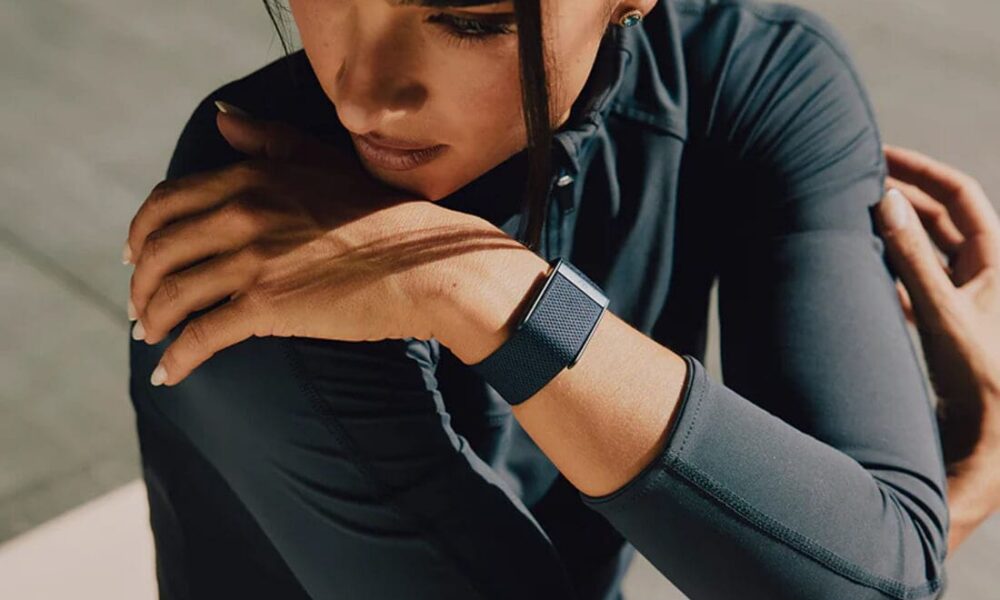 Femme étirant le bras avec montre connectée de fitness.