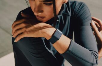Femme étirant le bras avec montre connectée de fitness.