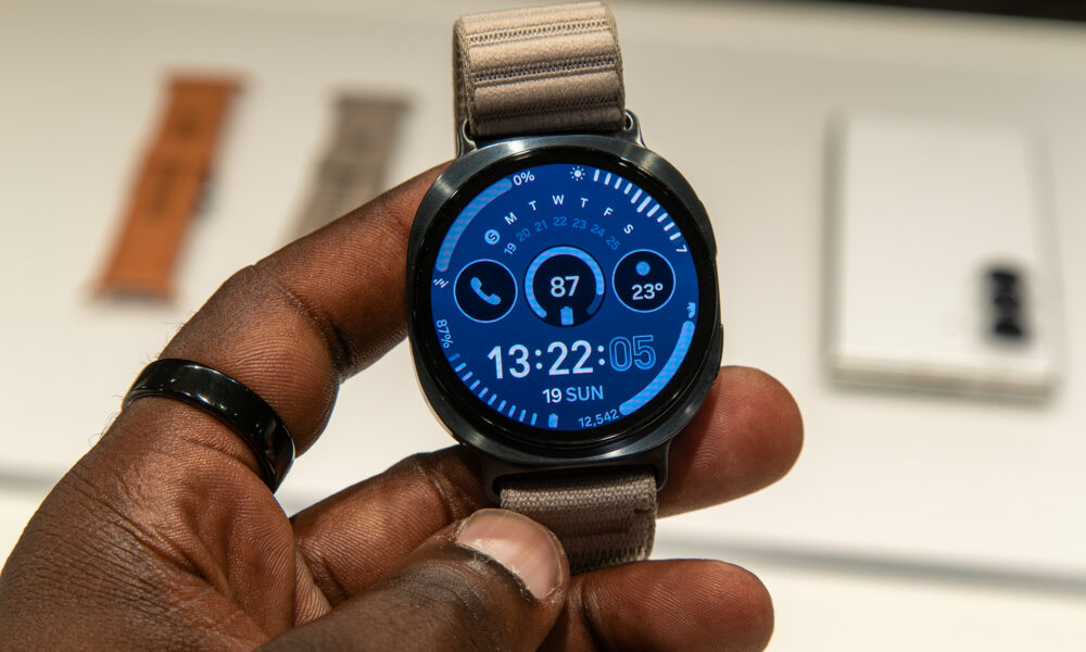 Main tenant une montre connectée avec écran bleu et bracelet en tissu.
