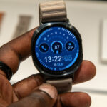 Galaxy Aero : Samsung préparerait une montre abordable sans Wear OS Main tenant une montre connectée avec écran bleu et bracelet en tissu.